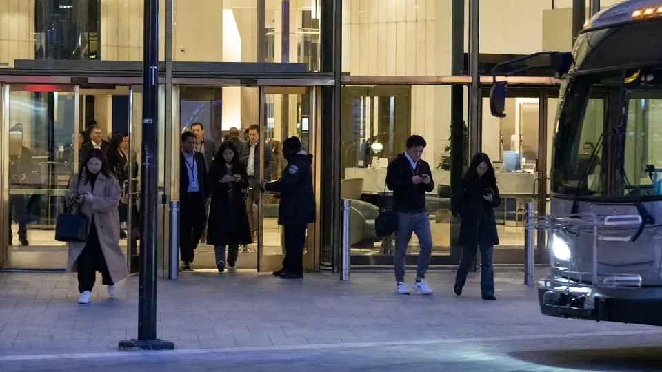 Office workers with lanyards leaving a glass tower in San Francisco at dusk, golden light on the brass door handles.