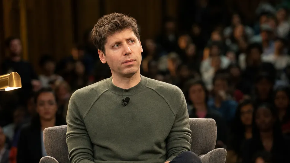 Sam Altman seated on a stage during a moderated conversation in front of a blurred audience.