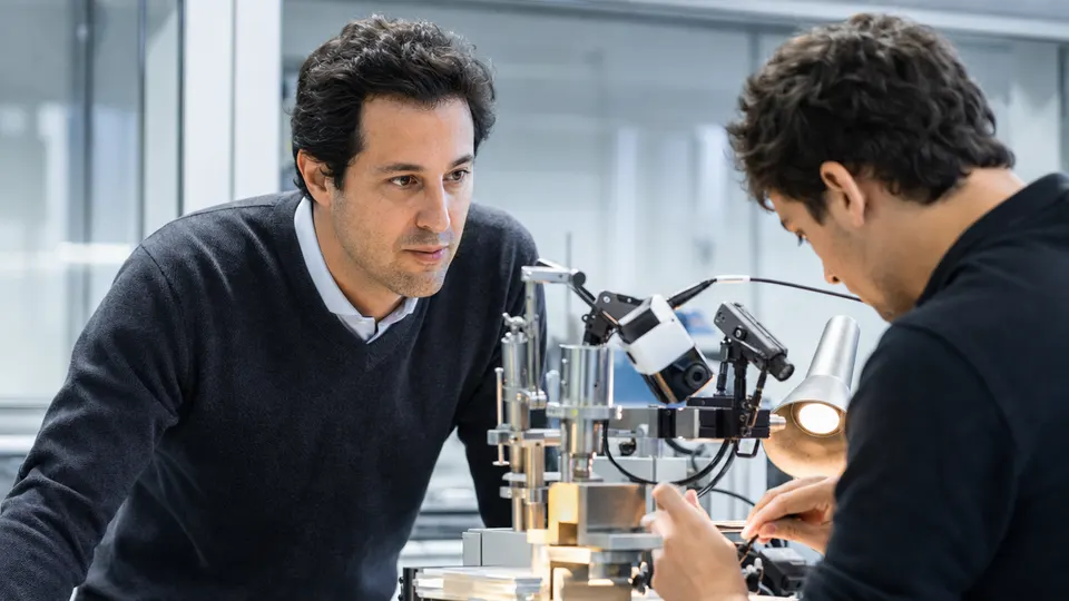 A researcher in a lab beside a compact motorized surgical rig with small cameras, illustrating the mouse gene therapy experiment.