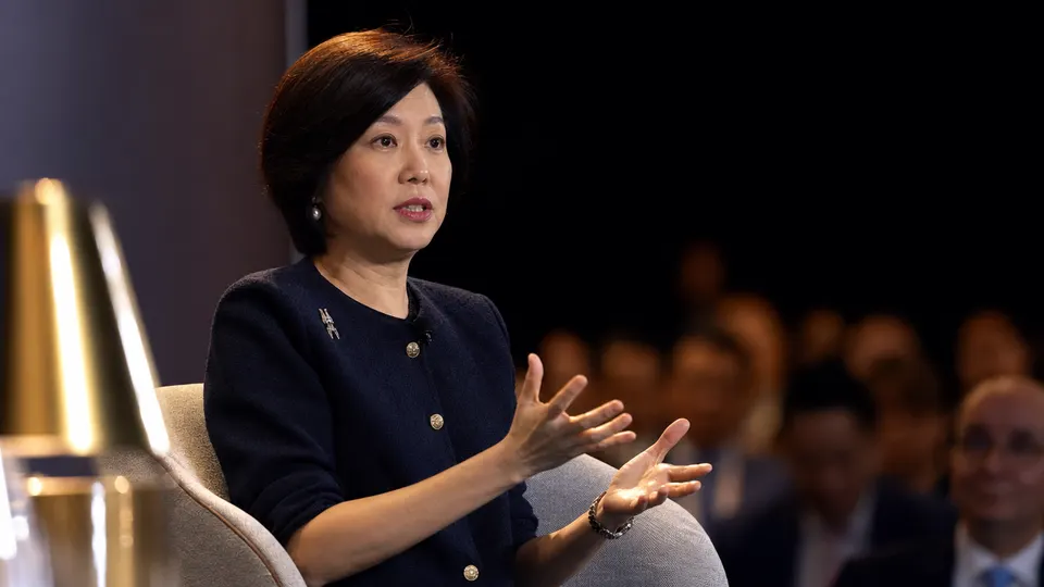 A banking executive speaks on a conference panel in Singapore under warm stage lighting.
