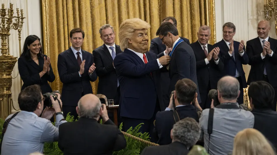 A caricature of President Donald Trump presenting a medal to a tech executive in a formal hall with applauding guests and photographers.