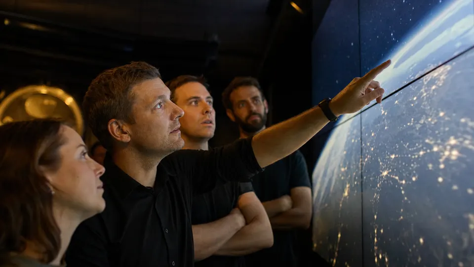 Engineers in a dim control room watching a wall display of Earth seen from orbit, illustrating Google's first AI satellite response.