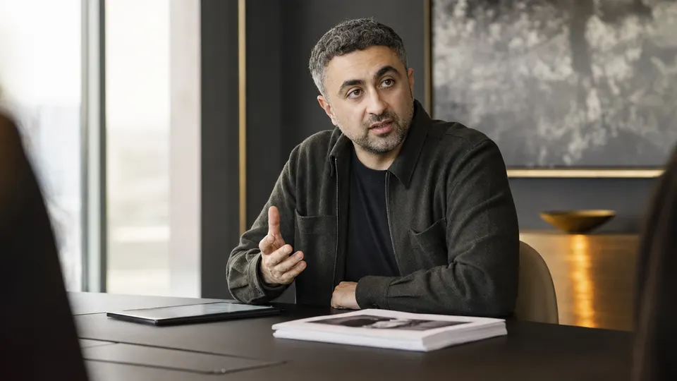 Illustrative photo of a Microsoft AI executive at a conference table reviewing case files and a tablet in a bright office.