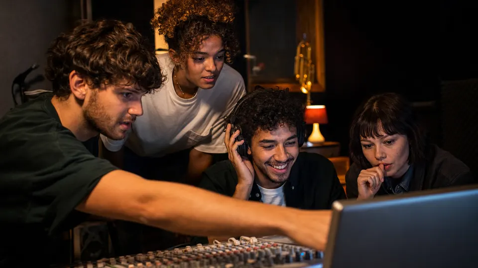 Musicians and a producer listening to a playback together in a home recording studio, illustrating fan-made song remixes.